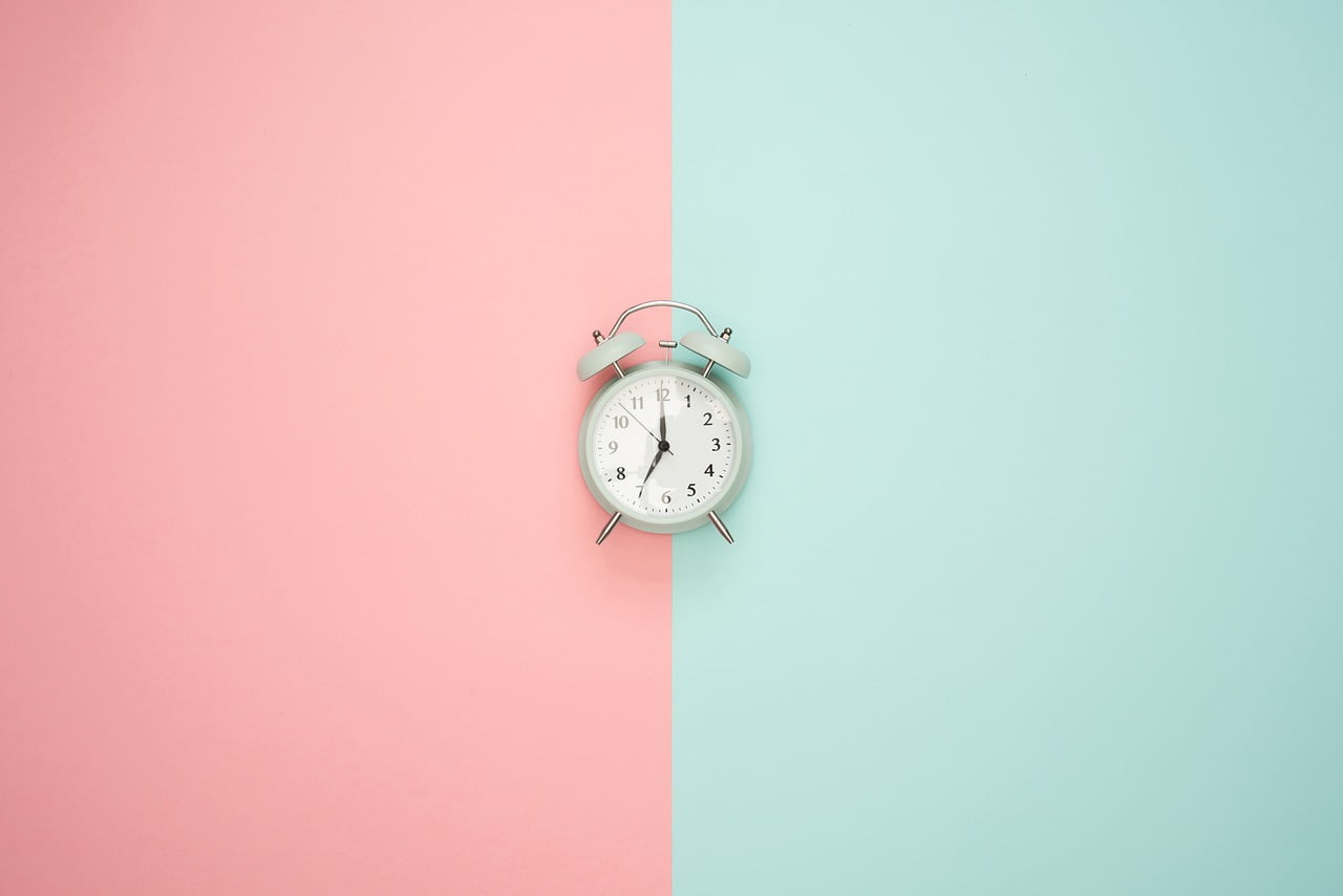 Zegar na ścianie w połowie różowej i w połowie zielonej, który sugeruje nastawienie zegara biologicznego