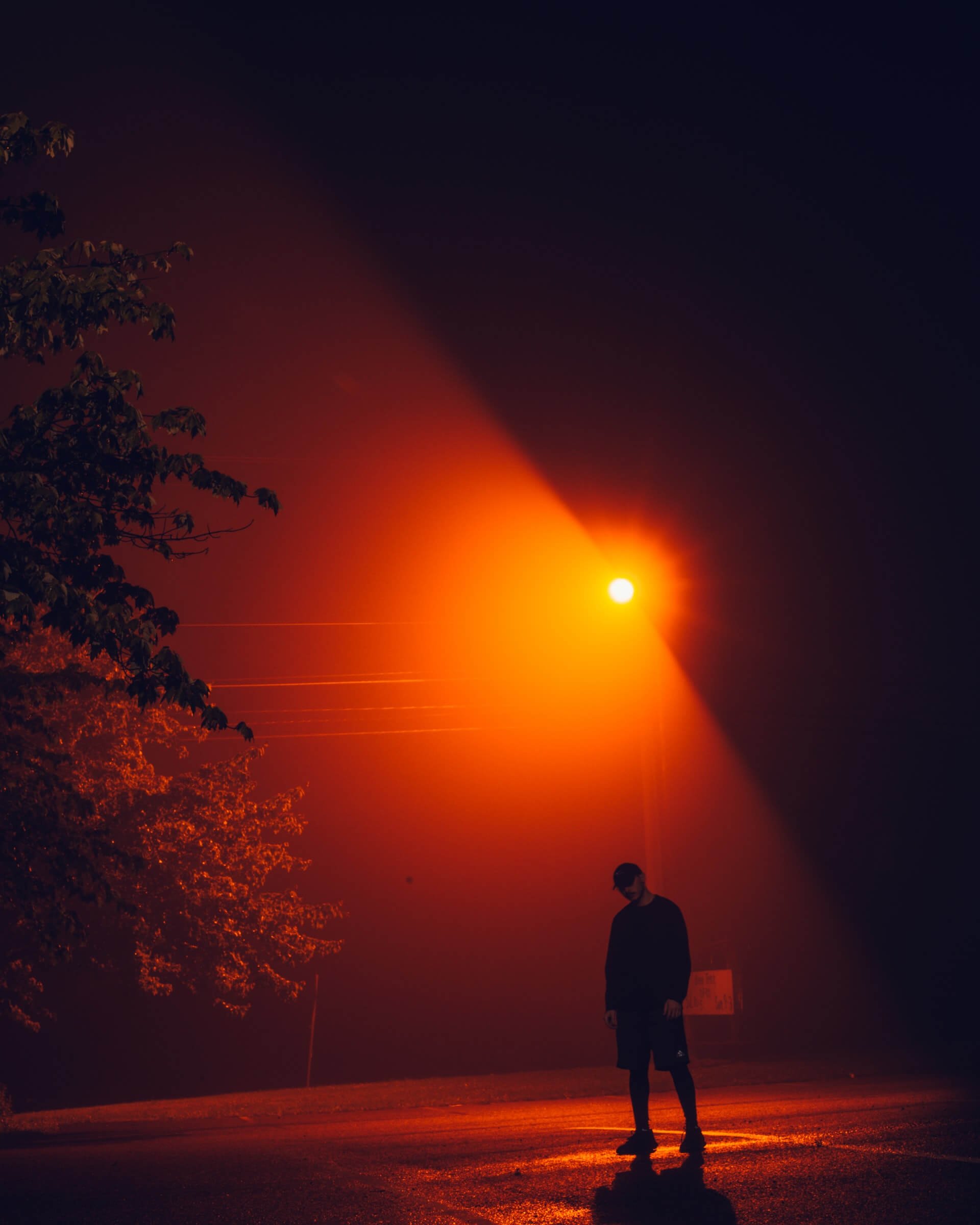 Mężczyzna w czarnym stroju stojący pod światłem czerwonem